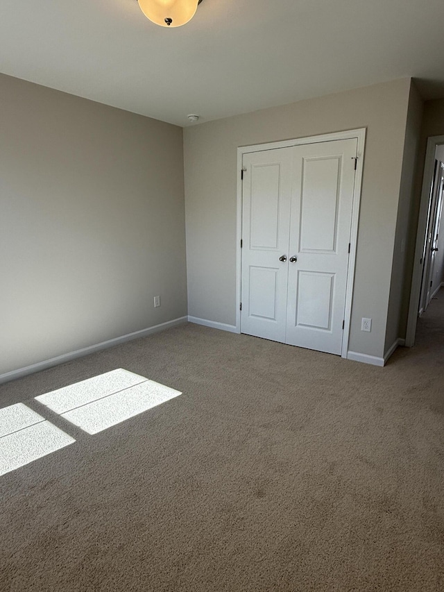 unfurnished bedroom with a closet, baseboards, and carpet