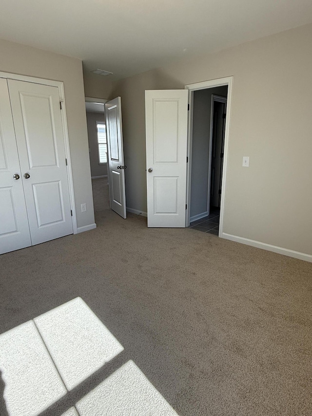 unfurnished bedroom with a closet, baseboards, and carpet floors