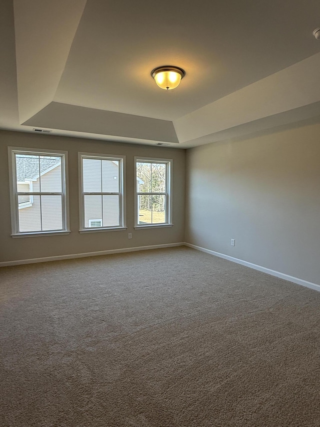 carpeted spare room with baseboards and a tray ceiling