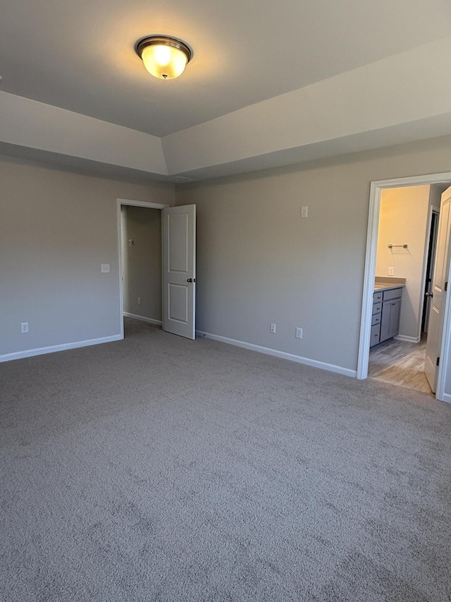 spare room featuring baseboards, light colored carpet, and a raised ceiling