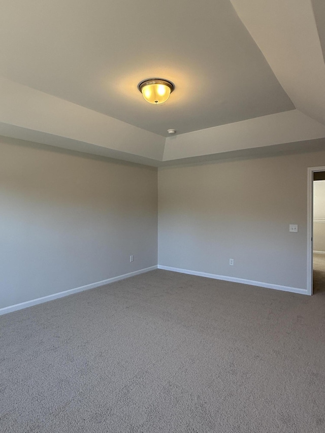 unfurnished room with a raised ceiling, baseboards, and carpet floors