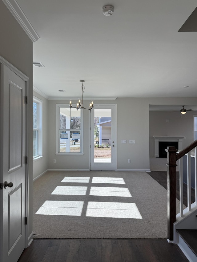 interior space with baseboards, visible vents, an inviting chandelier, a fireplace, and ornamental molding