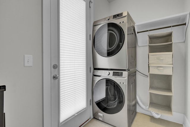 laundry room featuring light tile patterned floors and stacked washer / dryer