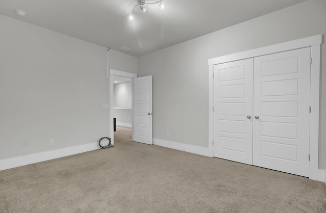 unfurnished bedroom with a closet and light colored carpet