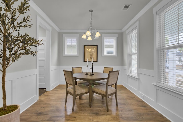 dining room with hardwood / wood-style floors, a chandelier, and crown molding