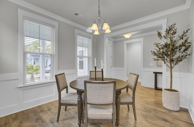 dining room with crown molding, an inviting chandelier, and wood-type flooring