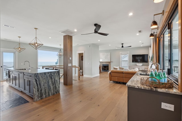 1568 E Ashley Ave, Folly Beach, SC 29439 - kitchen featuring a sink, a ceiling fan, open floor plan, light stone countertops, and light wood-style flooring