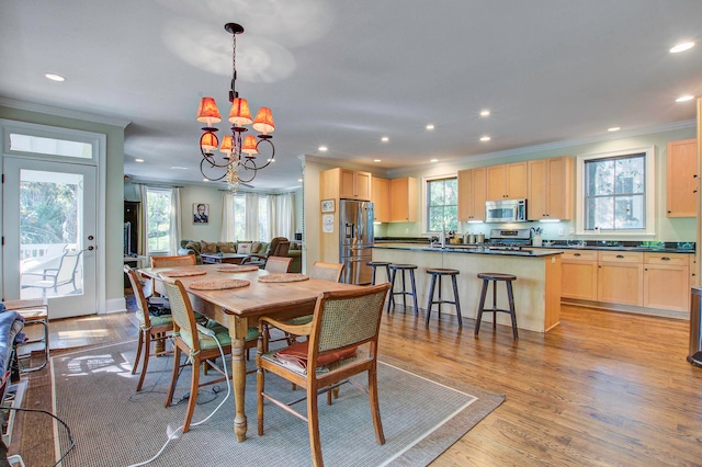 dining room with a wealth of natural light, an inviting chandelier, crown molding, and light wood-type flooring