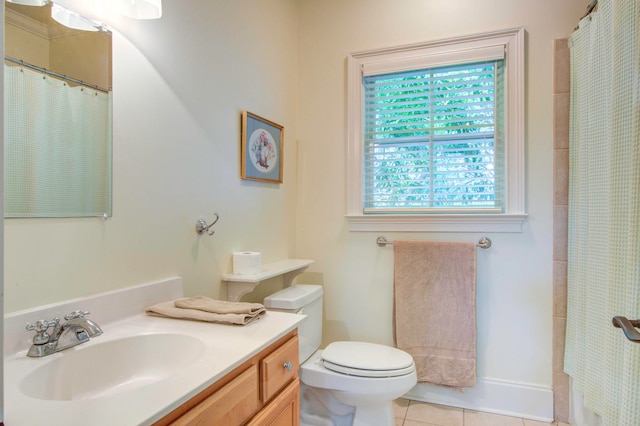 bathroom with tile flooring, a healthy amount of sunlight, vanity, and toilet