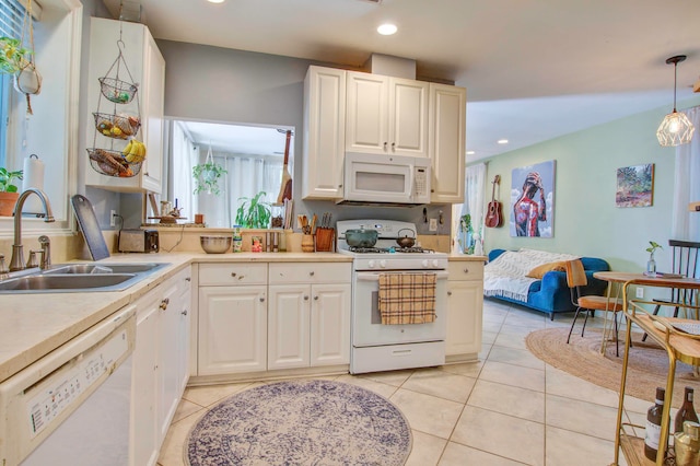 kitchen with hanging light fixtures, white appliances, white cabinetry, sink, and light tile floors