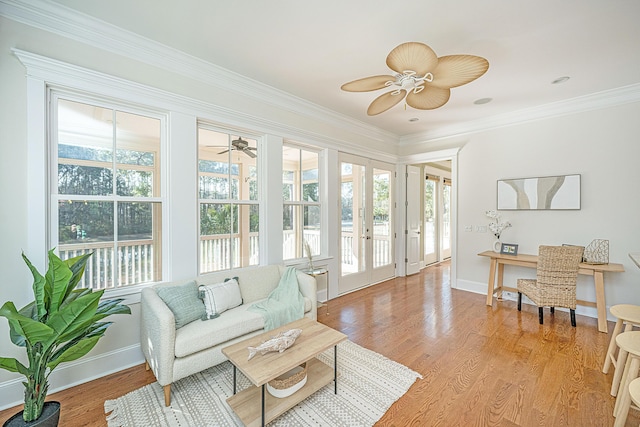 living room with ornamental molding, light wood finished floors, and ceiling fan