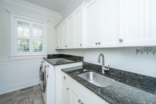 laundry area featuring cabinet space, wainscoting, a sink, stone finish flooring, and crown molding