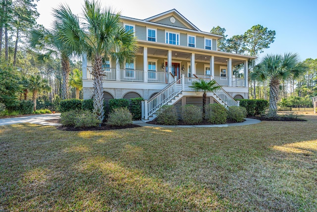 beach home featuring stairway, a porch, and a front lawn