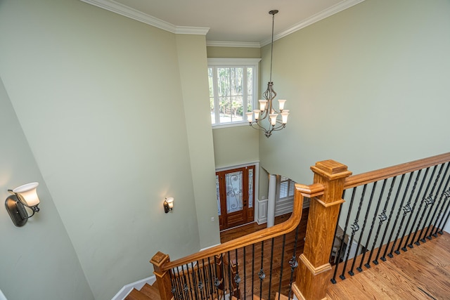 stairs featuring baseboards, an inviting chandelier, wood finished floors, and crown molding