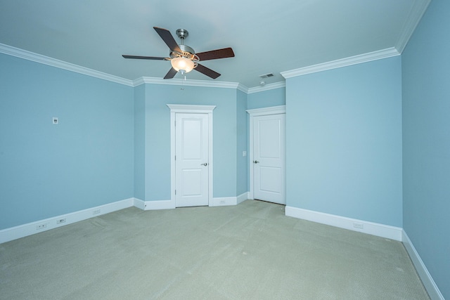 spare room featuring visible vents, light carpet, ornamental molding, baseboards, and ceiling fan