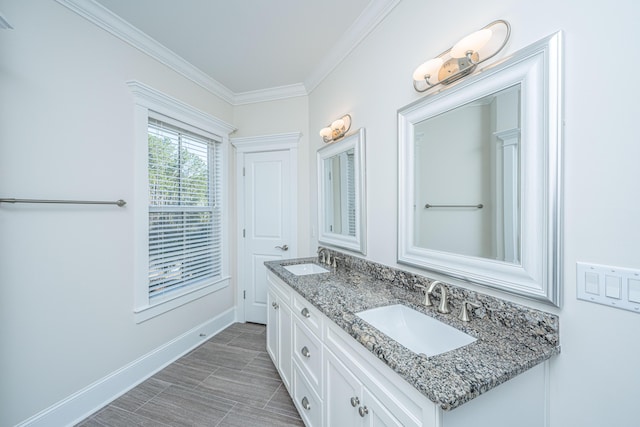 bathroom with a sink, baseboards, double vanity, and crown molding