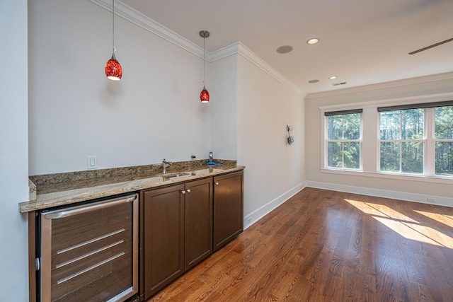 kitchen featuring wood finished floors, beverage cooler, baseboards, light stone countertops, and ornamental molding