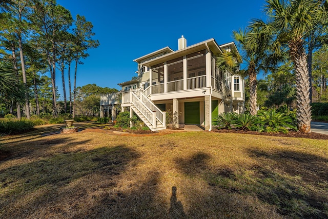 back of property with stairway, a lawn, a sunroom, and a chimney