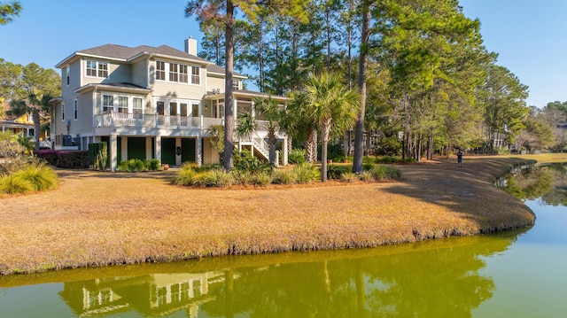 back of house with a deck with water view, a chimney, and stairs