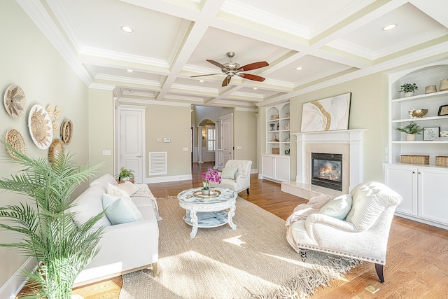 living area with visible vents, a premium fireplace, beam ceiling, light wood-style flooring, and arched walkways