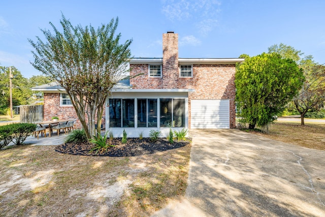 rear view of house featuring a garage and a sunroom