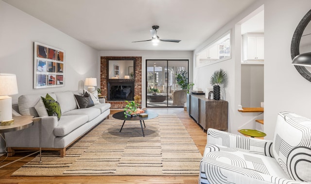 living room featuring ceiling fan, light hardwood / wood-style flooring, and a fireplace