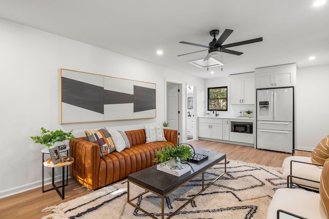 living room featuring sink, light hardwood / wood-style floors, and ceiling fan