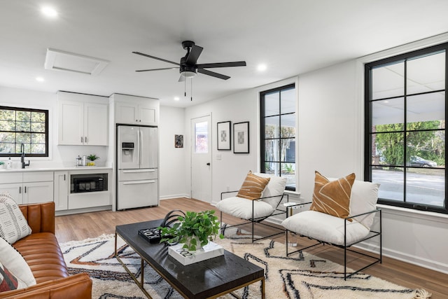 living room featuring sink, ceiling fan, and light hardwood / wood-style flooring