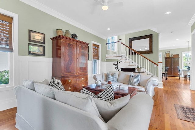 living room featuring ornamental molding, light hardwood / wood-style floors, and ceiling fan