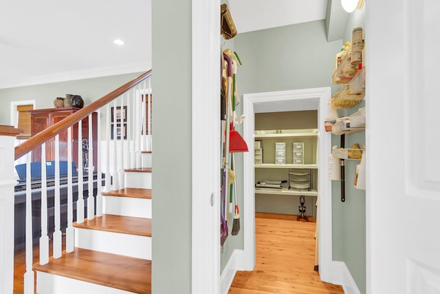 stairway featuring wood-type flooring and ornamental molding