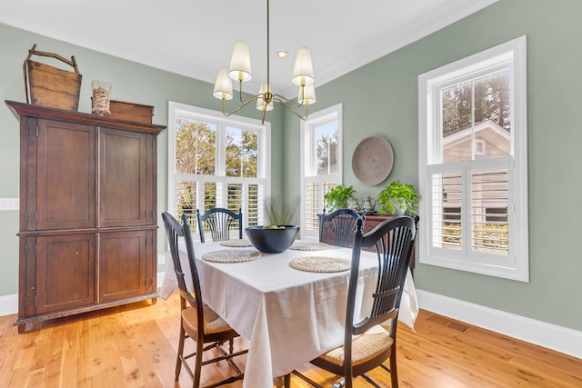 dining area featuring a chandelier, crown molding, and light hardwood / wood-style flooring