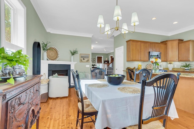 dining space with light hardwood / wood-style floors, an inviting chandelier, and ornamental molding