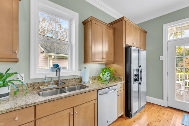 kitchen featuring sink, light stone counters, appliances with stainless steel finishes, light hardwood / wood-style flooring, and crown molding