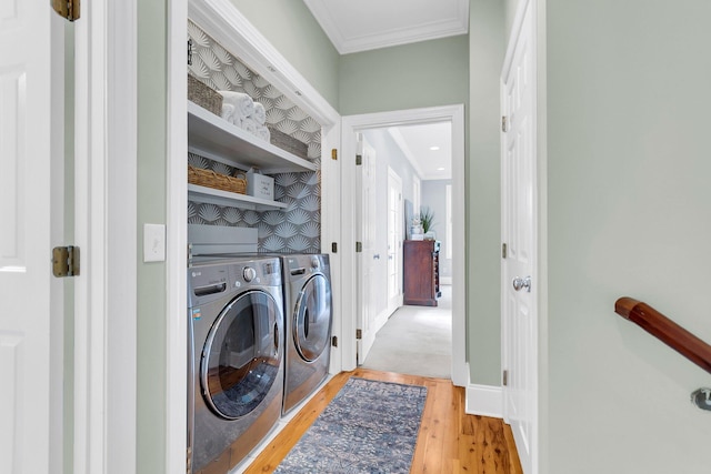 laundry area featuring light wood-type flooring, washer and dryer, and crown molding