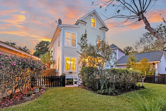 back house at dusk featuring a yard