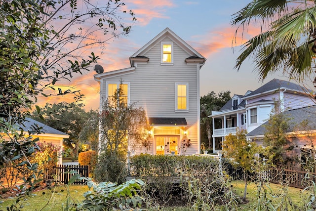 back house at dusk featuring a balcony