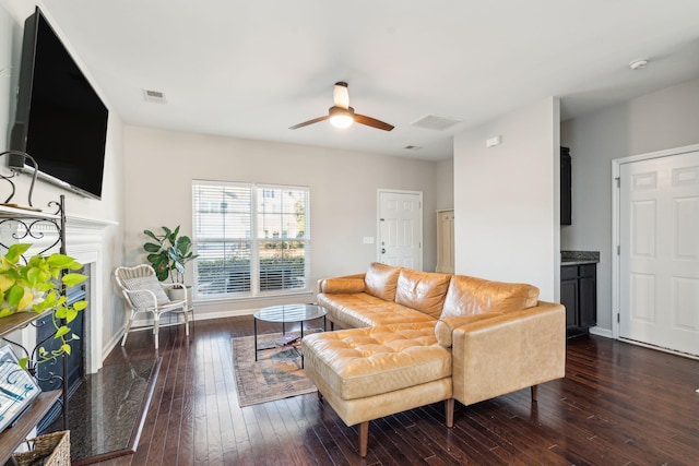 living room featuring a high end fireplace, ceiling fan, and dark wood-type flooring