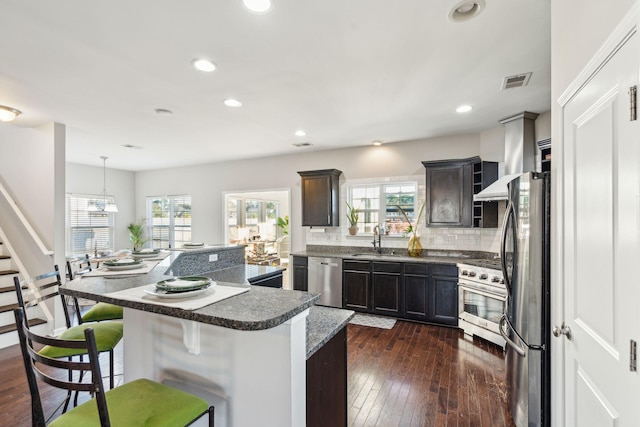 kitchen featuring sink, decorative light fixtures, a breakfast bar area, a kitchen island, and appliances with stainless steel finishes