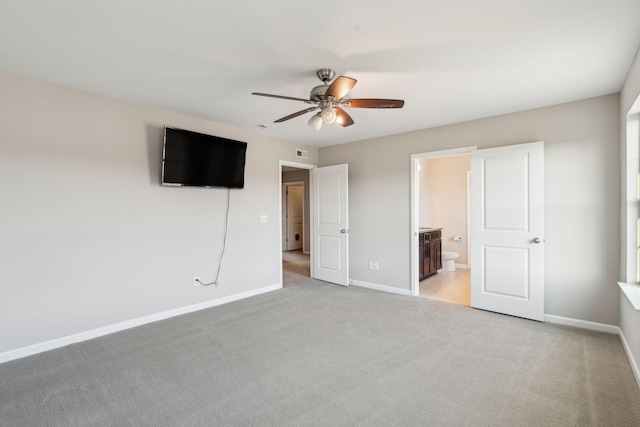 unfurnished bedroom with ceiling fan, light colored carpet, and ensuite bathroom