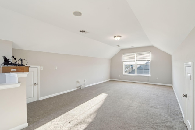 additional living space featuring vaulted ceiling and carpet flooring