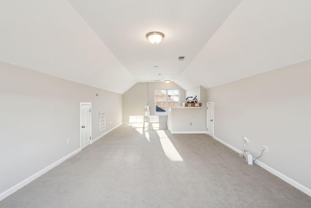 additional living space featuring light carpet and vaulted ceiling