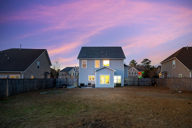 back house at dusk with a lawn