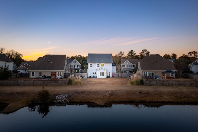 back house at dusk with a water view and a gazebo