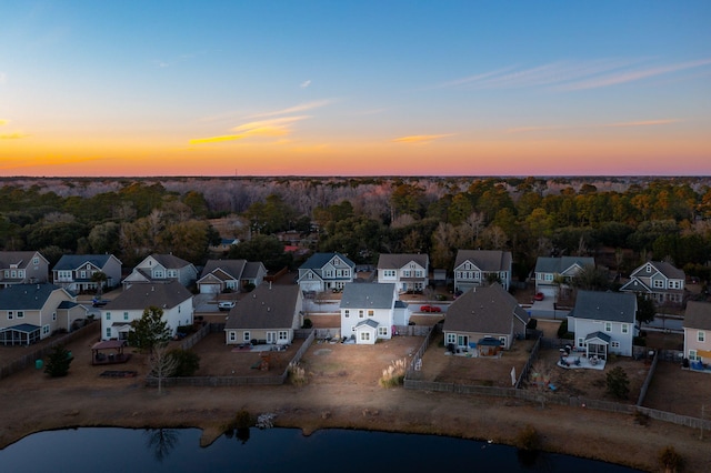 aerial view at dusk featuring a water view