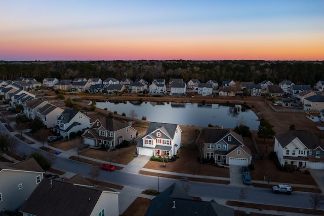 aerial view at dusk featuring a water view