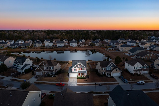 aerial view at dusk featuring a water view