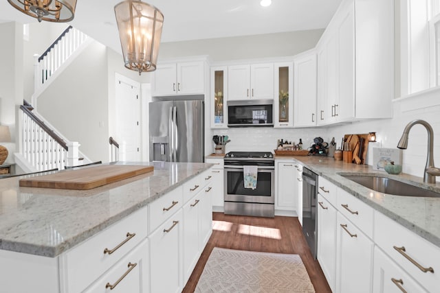 kitchen featuring hanging light fixtures, appliances with stainless steel finishes, white cabinetry, dark hardwood / wood-style floors, and sink