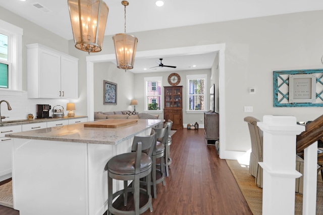 kitchen featuring a healthy amount of sunlight, decorative light fixtures, a kitchen island, and white cabinets