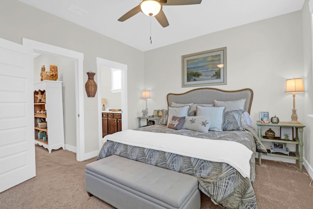 bedroom featuring light carpet, ceiling fan, and ensuite bath