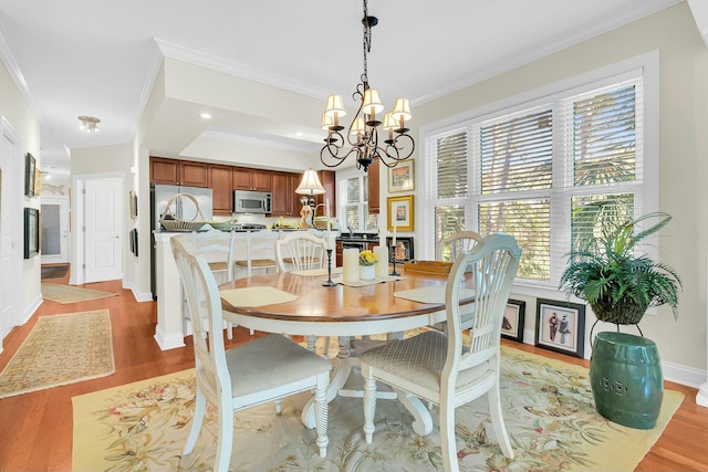 dining room featuring ornamental molding, a chandelier, and light hardwood / wood-style floors